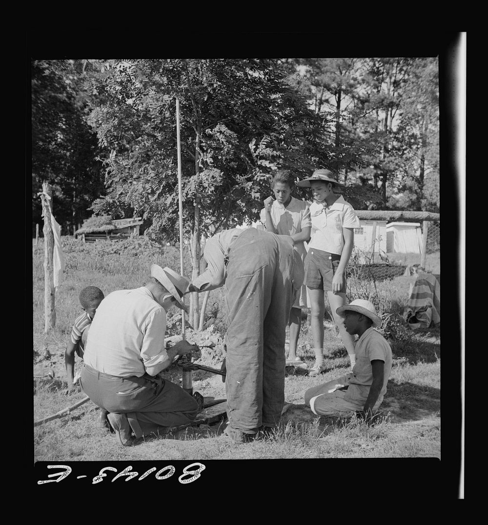 Everybody tries to learn. White FSA (Farm Security Administration)  engineer rigs pump. Ridge well project, Saint Mary's…