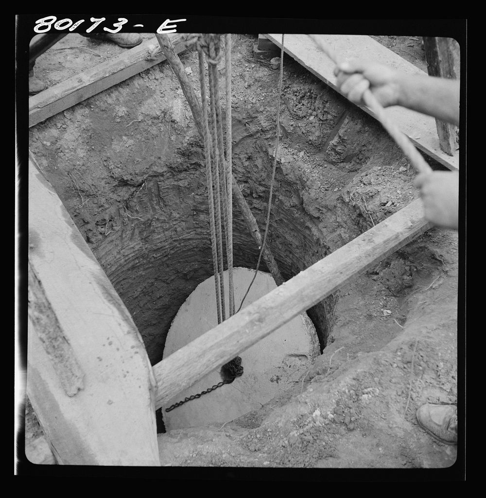 [Untitled photo, possibly related to: Block and tackle hung from windlass serve as a rig to lower cement cap into place.…