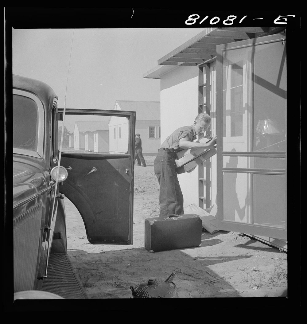Between shifts at the defense plant this FSA (Farm Security Administration) tenant moves into FSA defense housing project.…