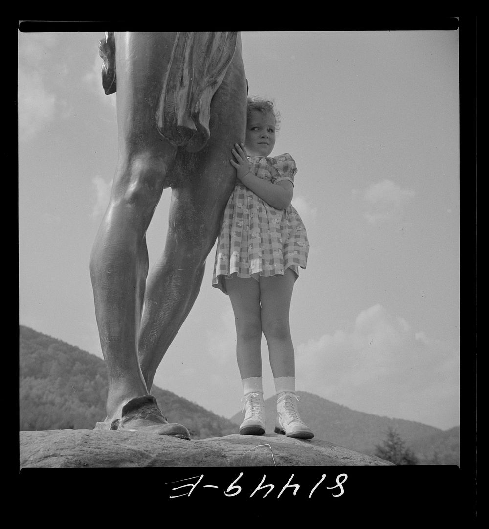 A little girl clinging to the bronze statue of an Indian on the Mohawk Trail in Massachusetts. Sourced from the Library of…