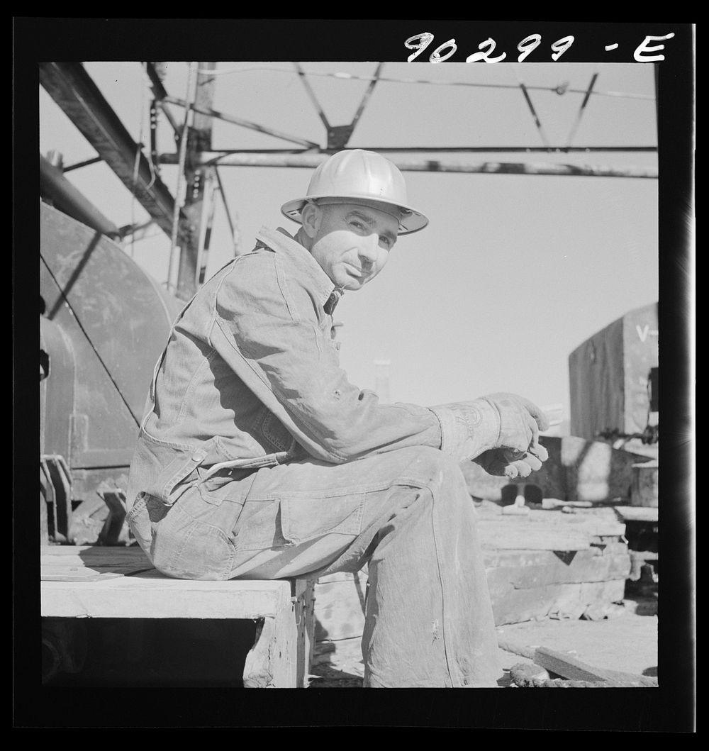 J.E. Schenermann, driller from Oklahoma, but worked in the Kansas oil fields about ten years; on pile of drill pipes near…