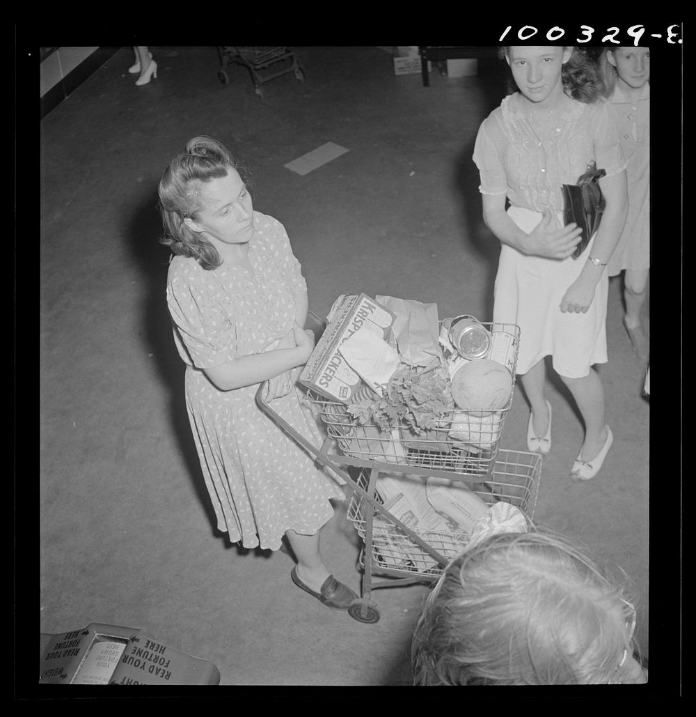Washington, D.C. Shopper waiting in line at a cashier's booth in the Giant Food shopping center. Sourced from the Library of…