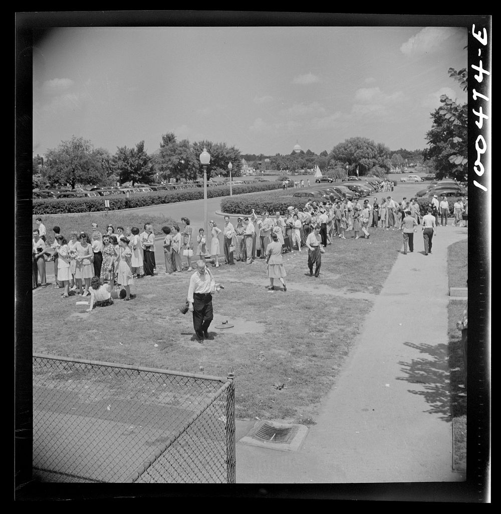 Washington, D.C. Line of prospective swimmers, awaiting their turn at the municipal swimming pool on Sunday. The Capitol is…