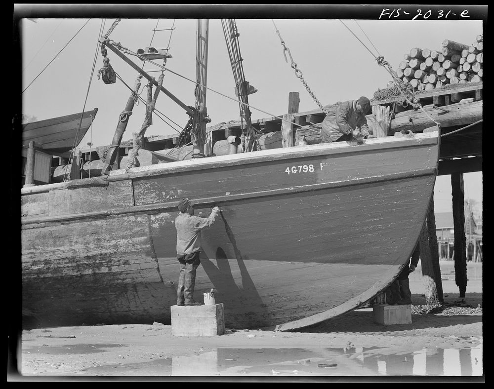 Provincetown, Massachusetts. The crew of the Frances and Marion, a Portuguese trawler, painting ship on the beach. Sourced…