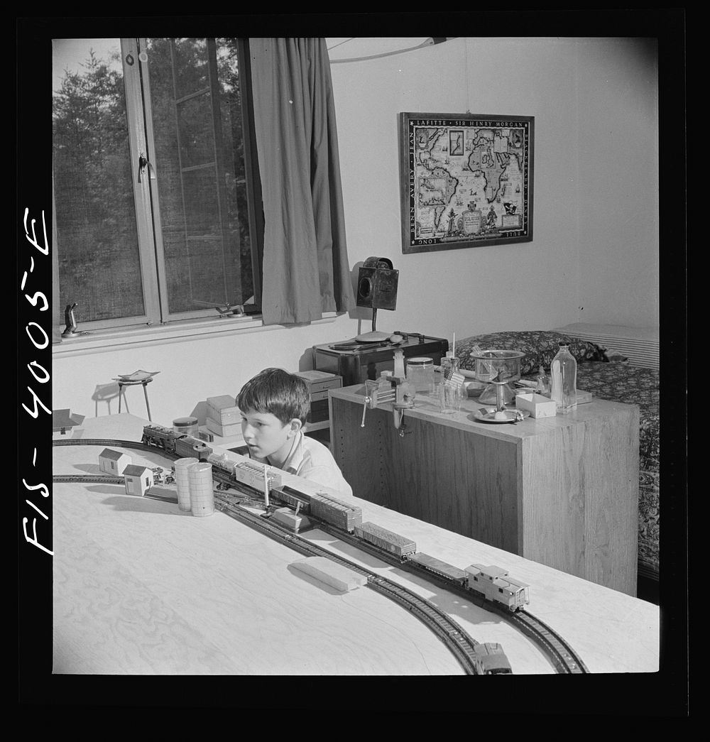 Greenbelt, Maryland. Child's bedroom in a house in which a thirteen year-old boy has rigged up model trains and a chemical…