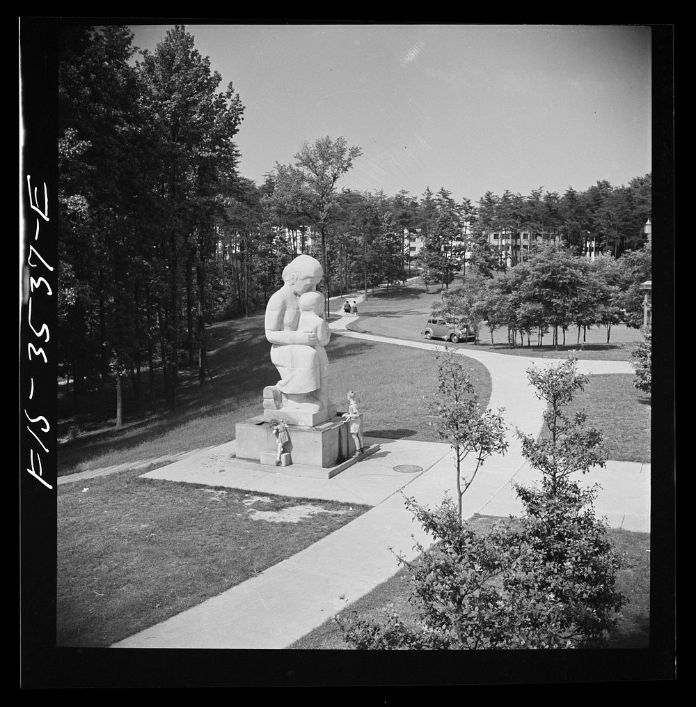 Greenbelt, Maryland. Federal housing project. View from roof of shopping center showing statue of a mother and child with a…