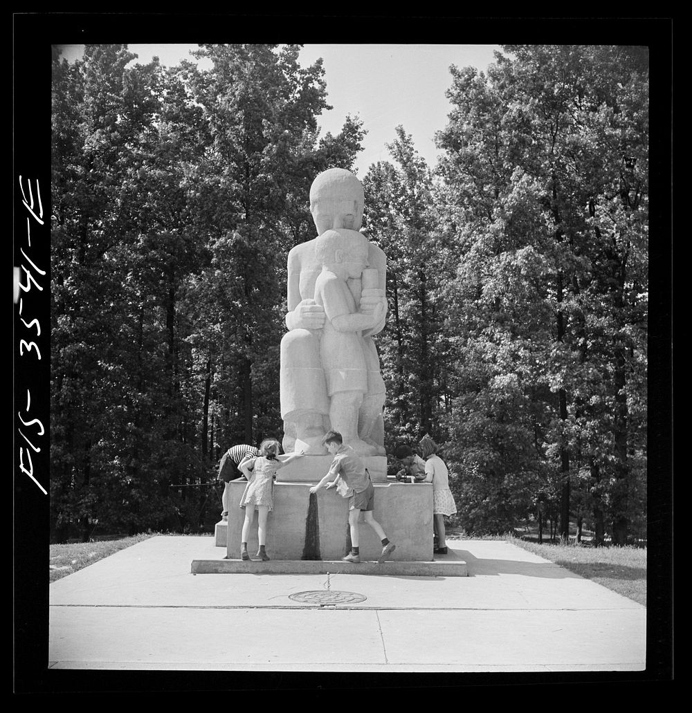 Greenbelt, Maryland. Federal housing project. Children at the drinking fountain in the shopping center square. Playground is…