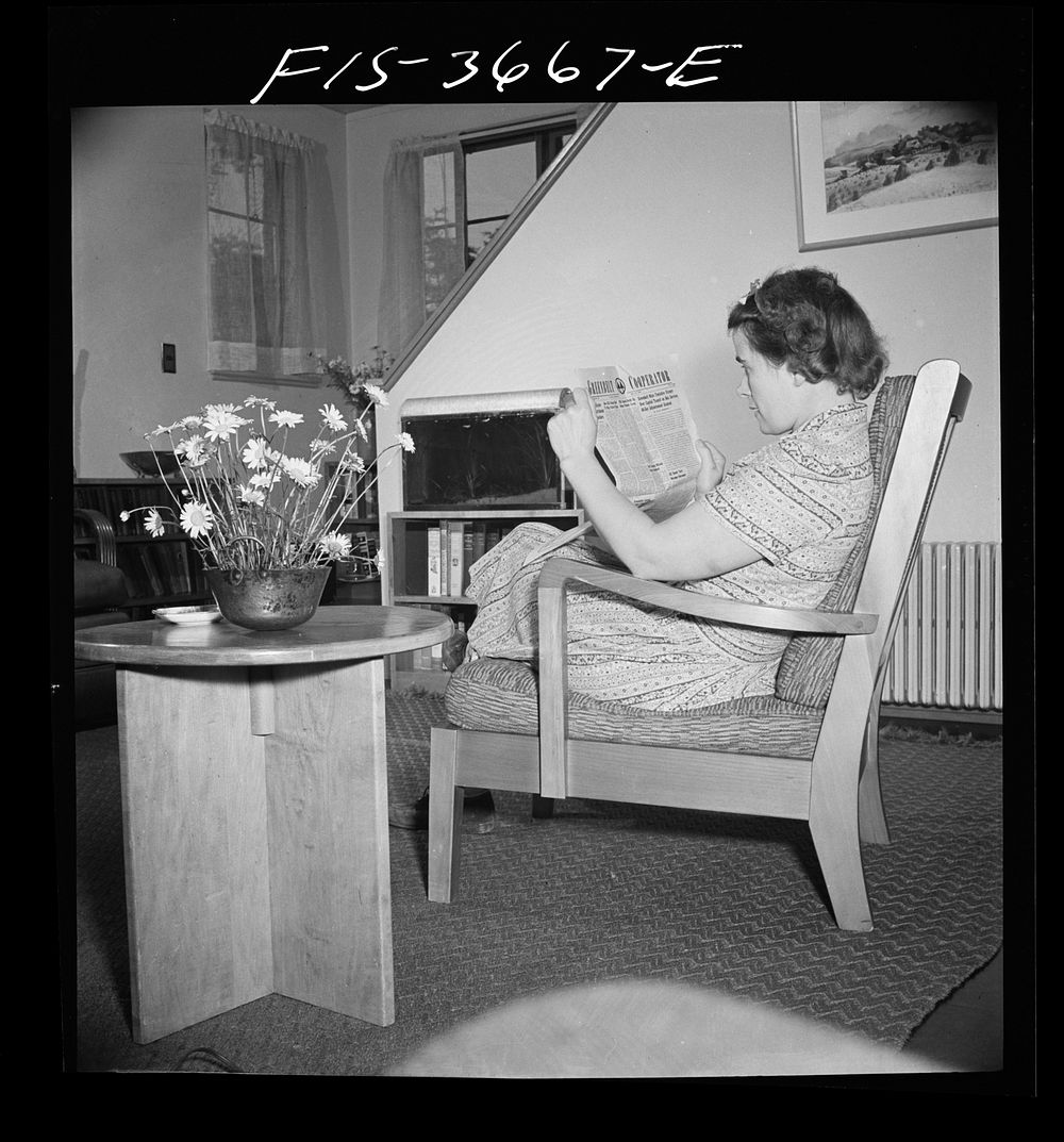 Greenbelt, Maryland. Mrs. Hoover reading a copy of the Greenbelt Cooperator. The chair and table are special skills…