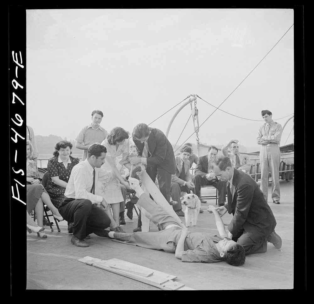 Washington, D.C. Applying a splint to a "broken" leg as part of a course in first aid, aboard a Potomac River boat. Sourced…