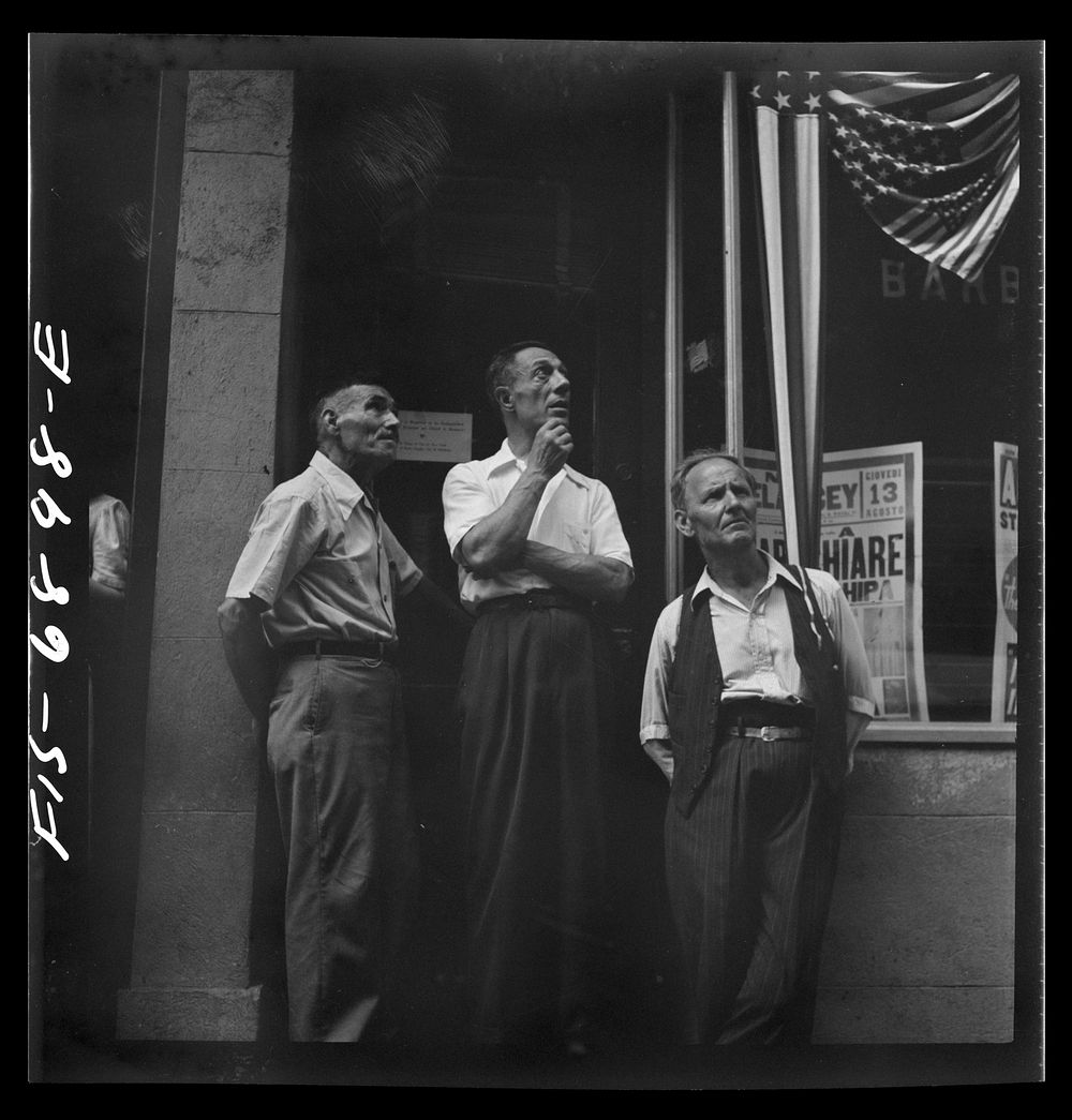 New York, New York. Italian-Americans in the rain watching a flag raising ceremony in honor of the feast of San Rocco at…