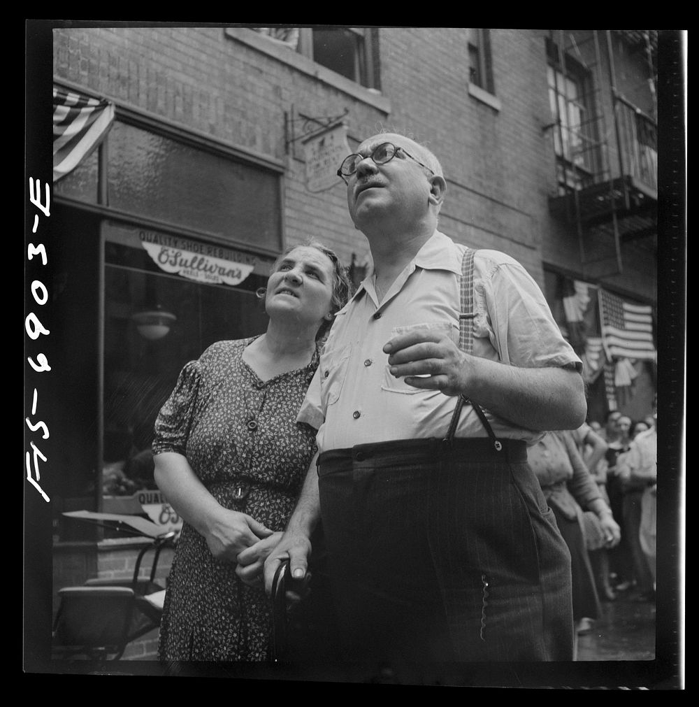 New York, New York. Italian-Americans in the rain watching a flag raising ceremony in honor of the feast of San Rocco at…