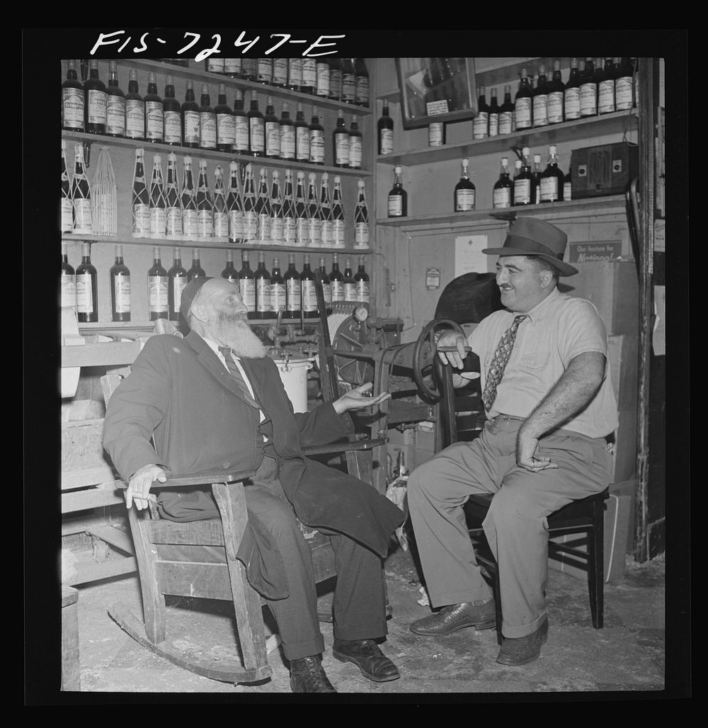 New York, New York. Rabbi in the Jewish section passing the time of day with the proprietor of a kosher wine shop where…