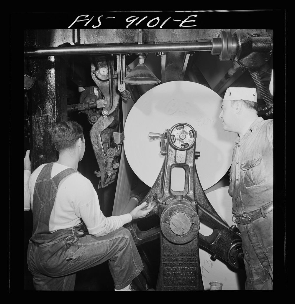 New York, New York. Reel room of the New York Times newspaper. In threading paper through presses two rolls of paper are…