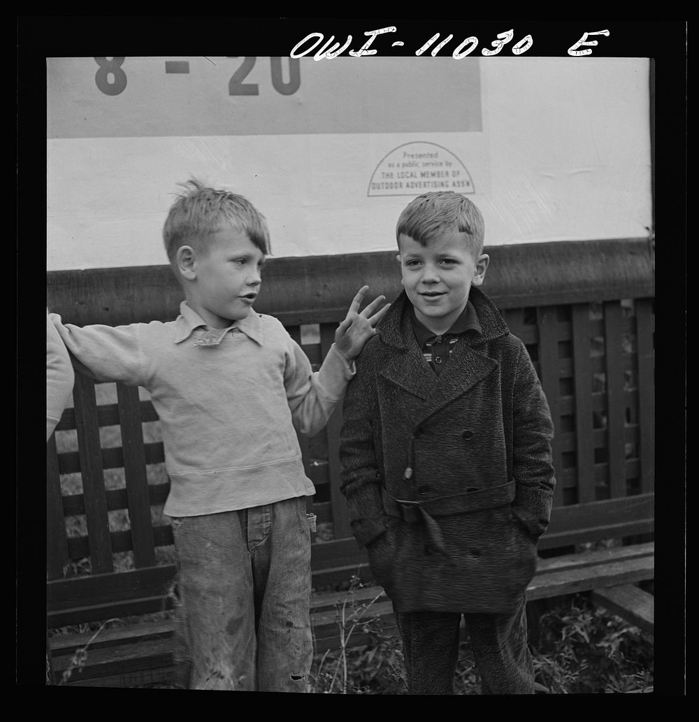 Lititz (vicinity), Pennsylvania. Boys playing near a billboard. Most of their fathers work in nearby defense plants. Sourced…