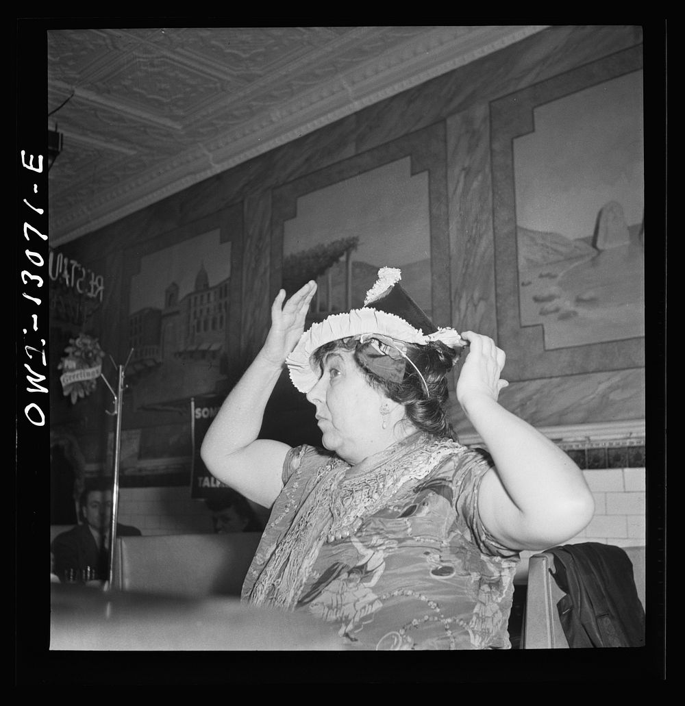 New York, New York. Gypsy woman putting on a paper cap on New Years' Eve in an Italian restaurant on Mulberry Street.…