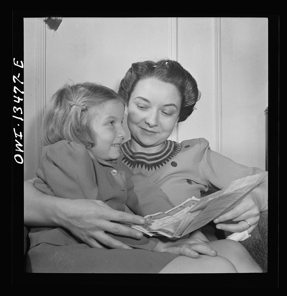 [Untitled photo, possibly related to: New York, New York. Martinetti's daughter and granddaughter examining a bond the child…