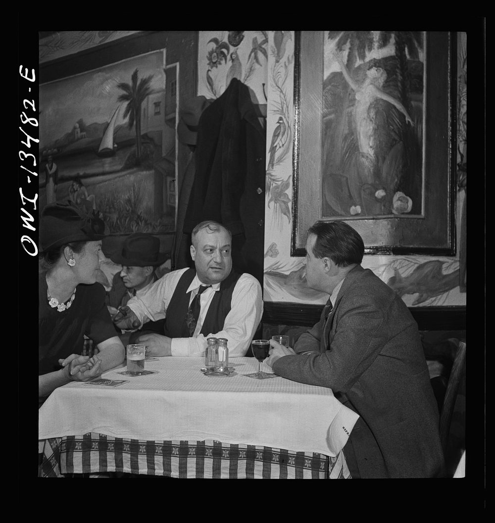 New York, New York. Jo Levy, owner of a Turkish nightclub on Allen Street, talking with guests. Sourced from the Library of…