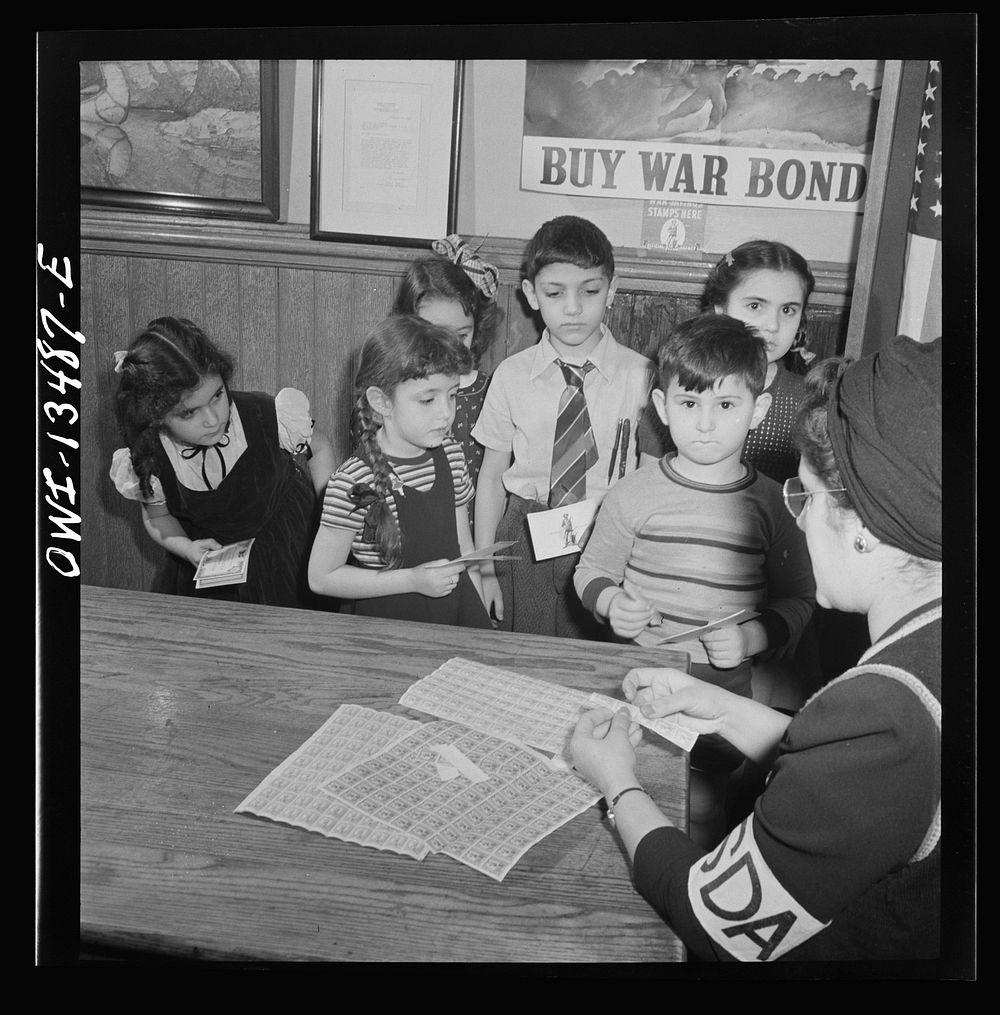 New York, New York. Italian-American children buying stamps and bonds at Public School Eight on King Street from mothers who…