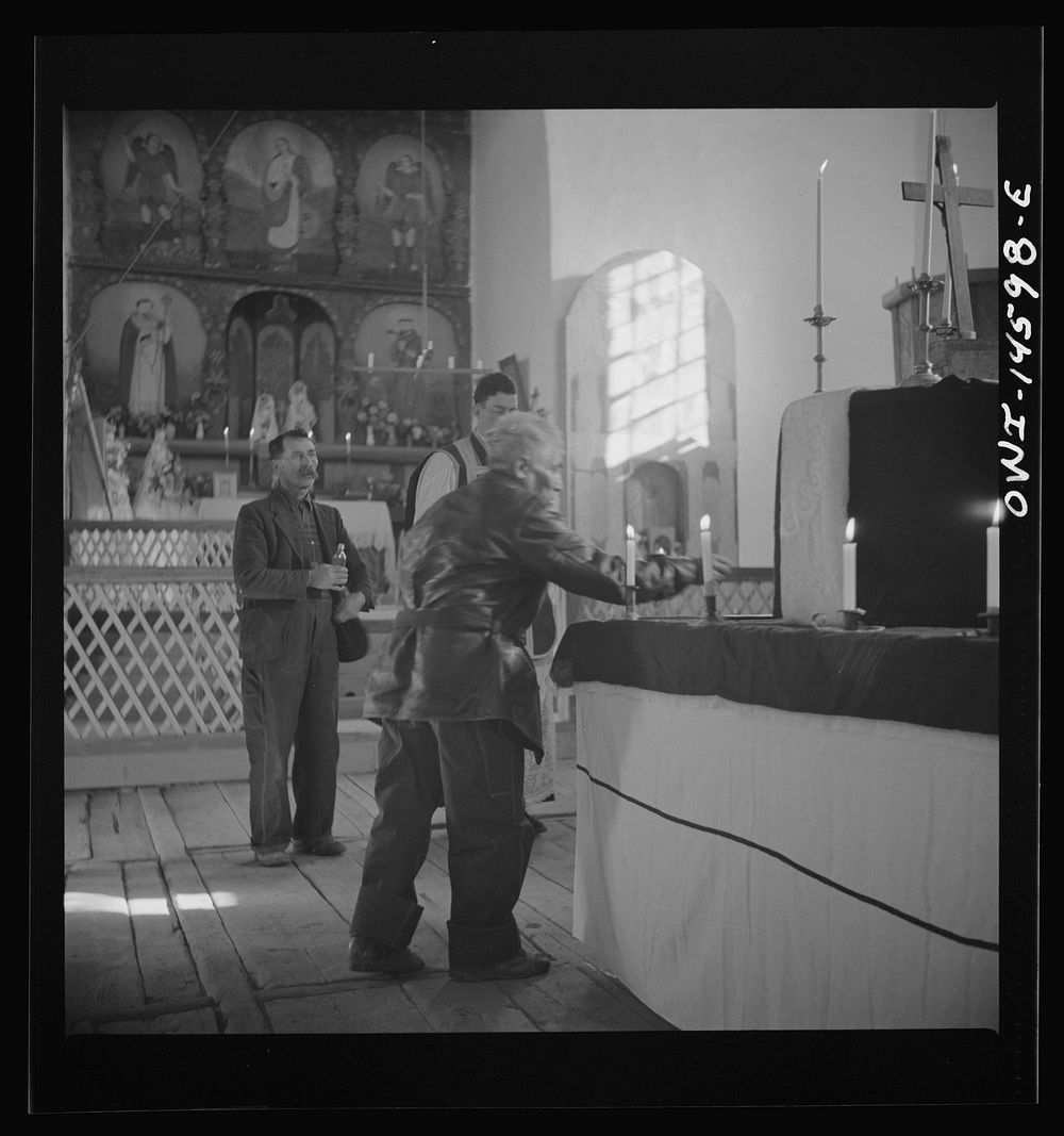 Trampas, New Mexico. Member of the congregation leaving an offering during a memorial mass in church which was built in 1700…