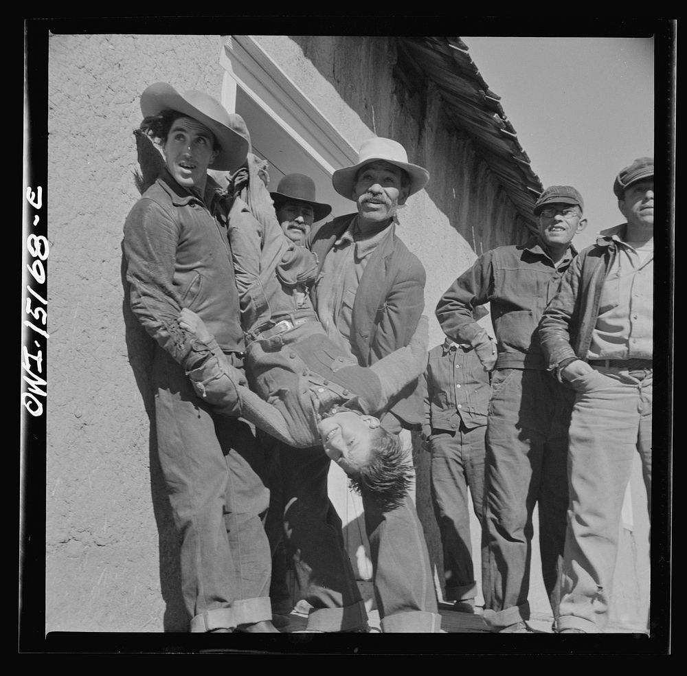 Chacon, Mora County, New Mexico. Idlers at the general store holding a small boy for the photographer. Sourced from the…