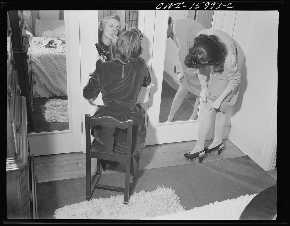 Detroit, Michigan. Girl putting on lipstick and another girl straightening seams in her stocking. Sourced from the Library…