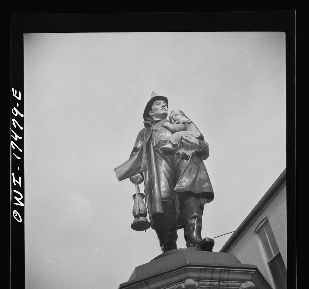 Carlisle, Pennsylvania. Polychrome statue of a fireman rescuing a child outside the firehouse. Sourced from the Library of…