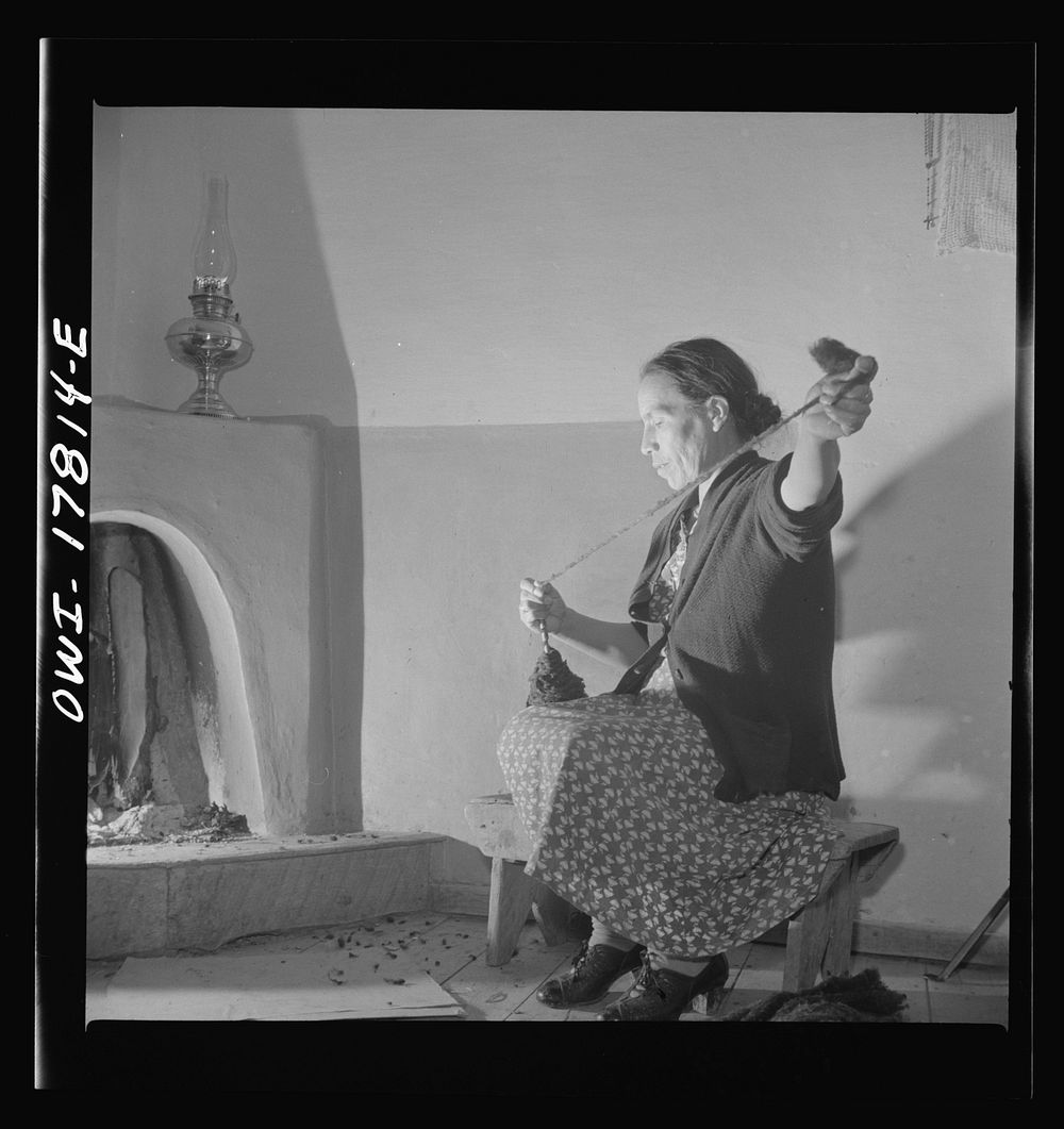 Trampas, New Mexico. Maclovia Lopez, wife of the majordomo (mayor), spinning wool by the light of the fire. The family has…