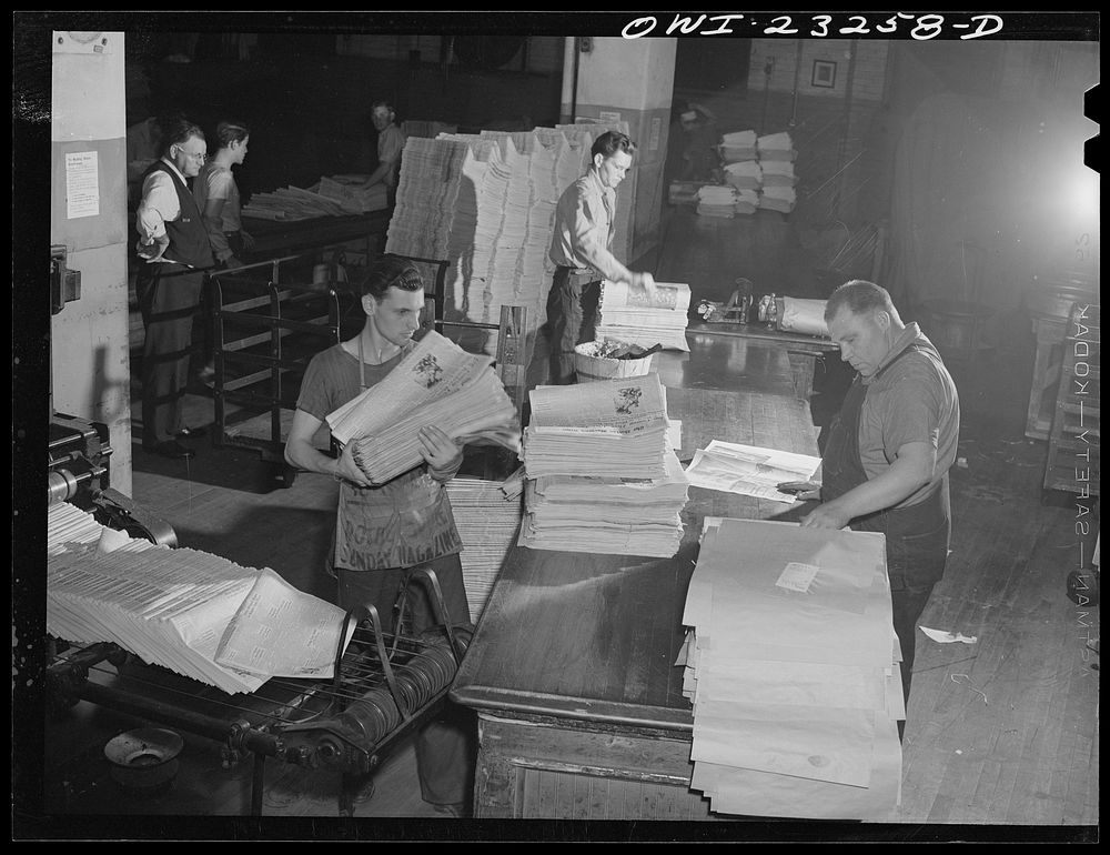 Dallas, Texas. Mail room at the Dallas Morning News. In the lower left corner papers are coming up off the presses. Sourced…