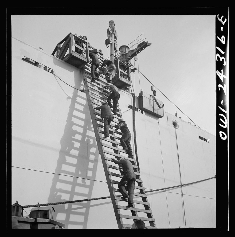 Bethlehem-Fairfield shipyards, Baltimore, Maryland. Workers descending a ladder at the outfitting pier. Sourced from the…