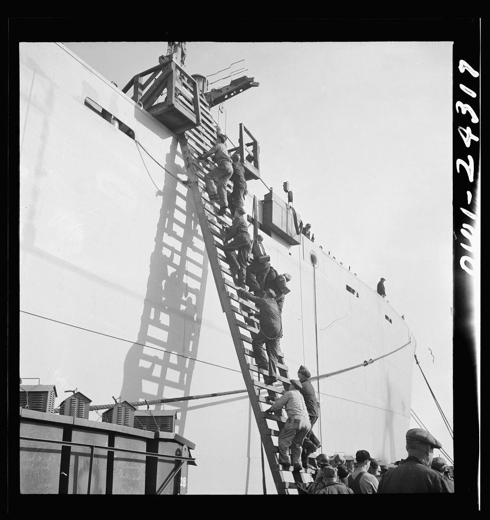 Bethlehem-Fairfield shipyards, Baltimore, Maryland. Workers ascending a ladder at the outfitting pier. Sourced from the…