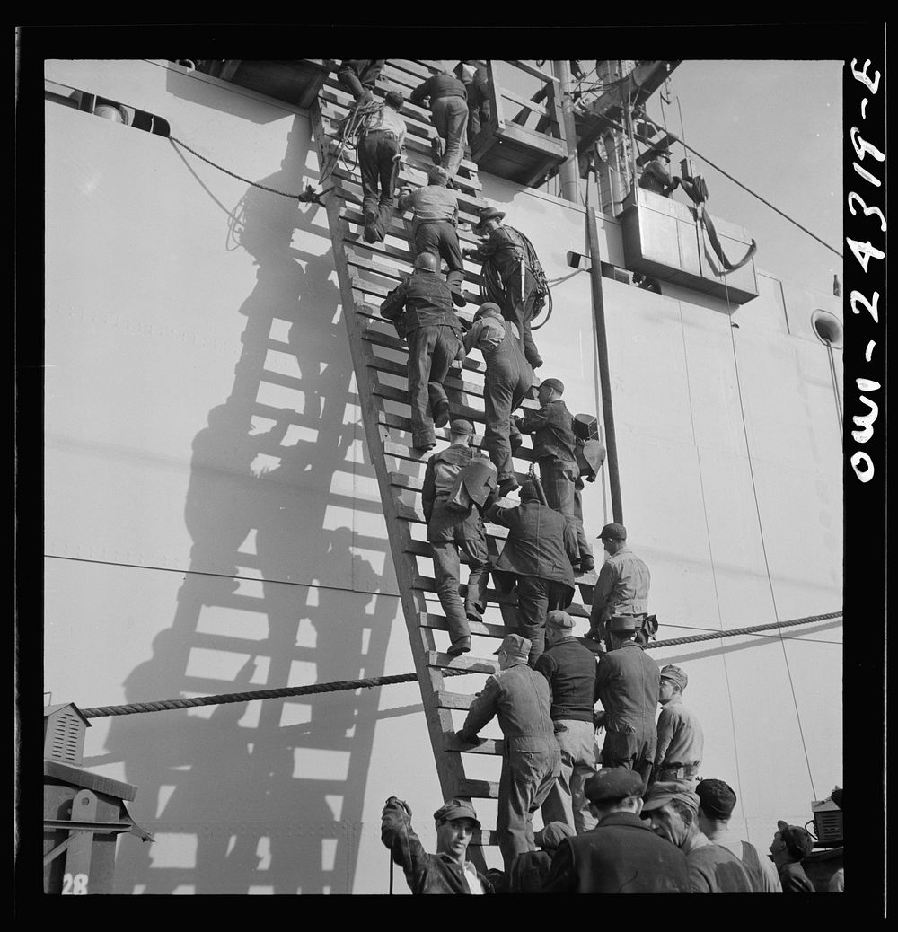 Bethlehem-Fairfield shipyards, Baltimore, Maryland. Workers on a ladder at the outfitting pier. Sourced from the Library of…
