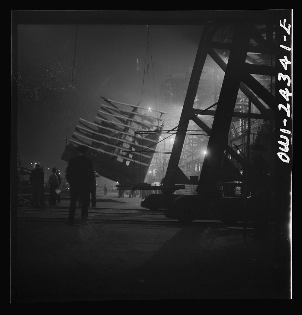 Bethlehem-Fairfield shipyards, Baltimore, Maryland. Lifting an after peak section at night. Sourced from the Library of…