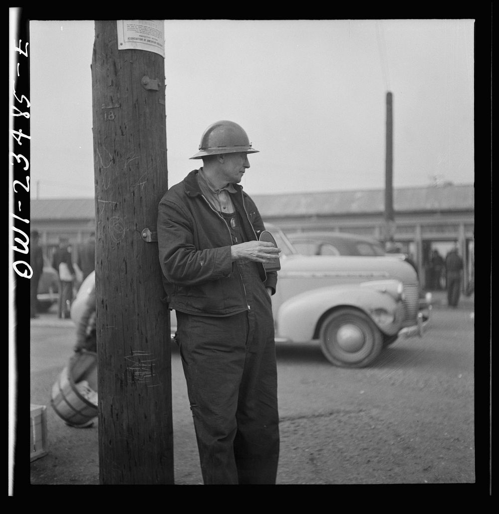 Bethlehem-Fairfield shipyards, Baltimore, Maryland. A shipyard worker looking at a time clock from outside of the yard.…