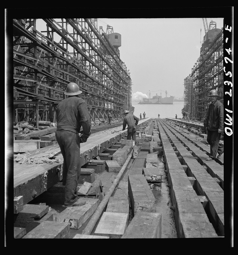 Bethlehem-Fairfield shipyards, Baltimore, Maryland. Workers removing grease from the ways after a ship launching ceremony.…