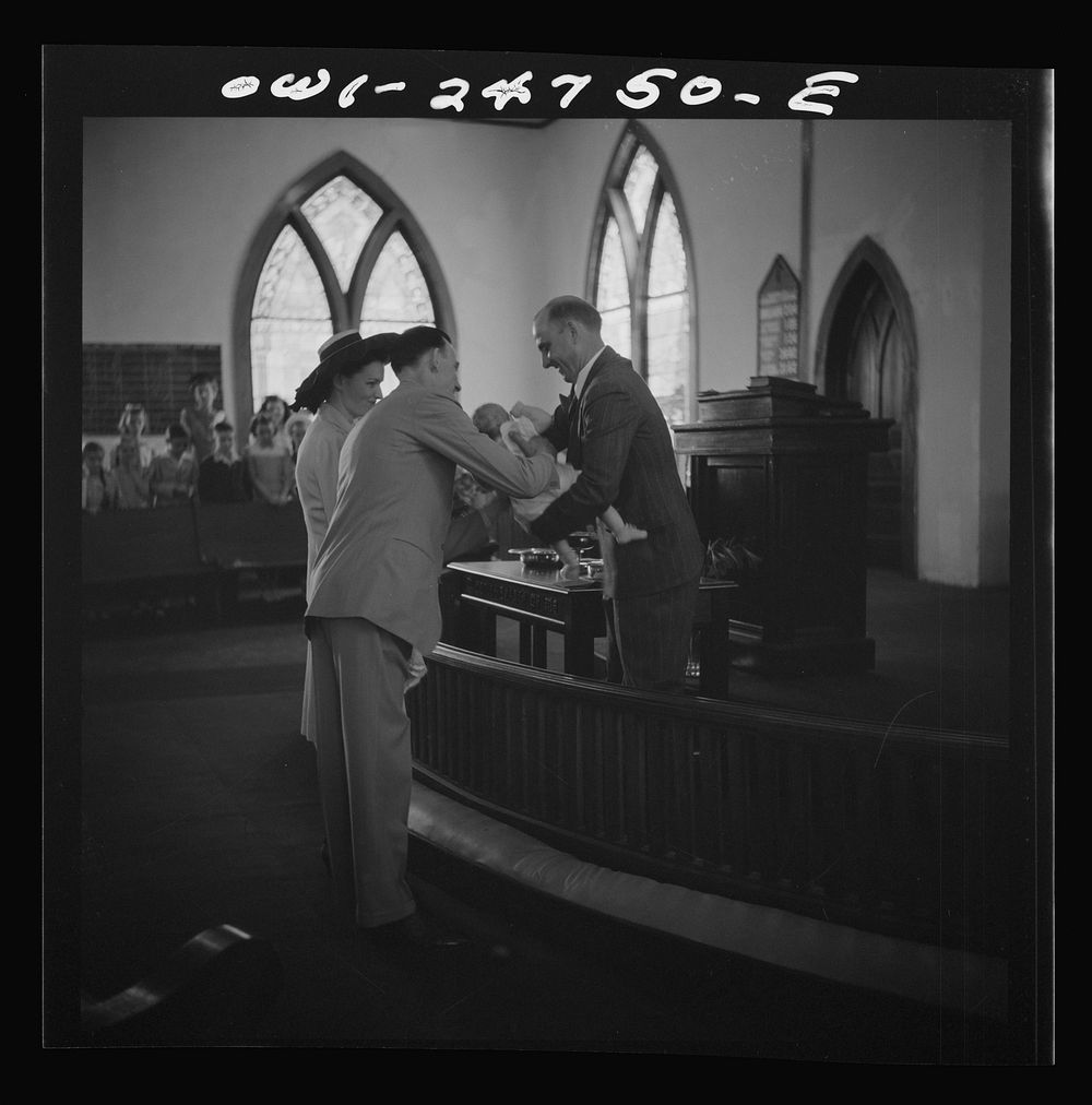 San Augustine, Texas. Reverend Dubberly taking an infant from its parents for the baptismal ceremony. Sourced from the…