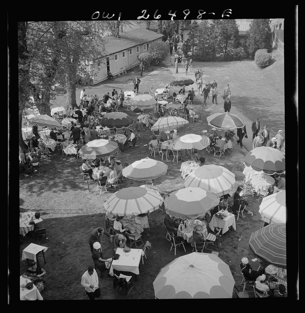 [Untitled photo, possibly related to: Pimlico racetrack, near Baltimore, Maryland. Outdoor diner sitting under beach…