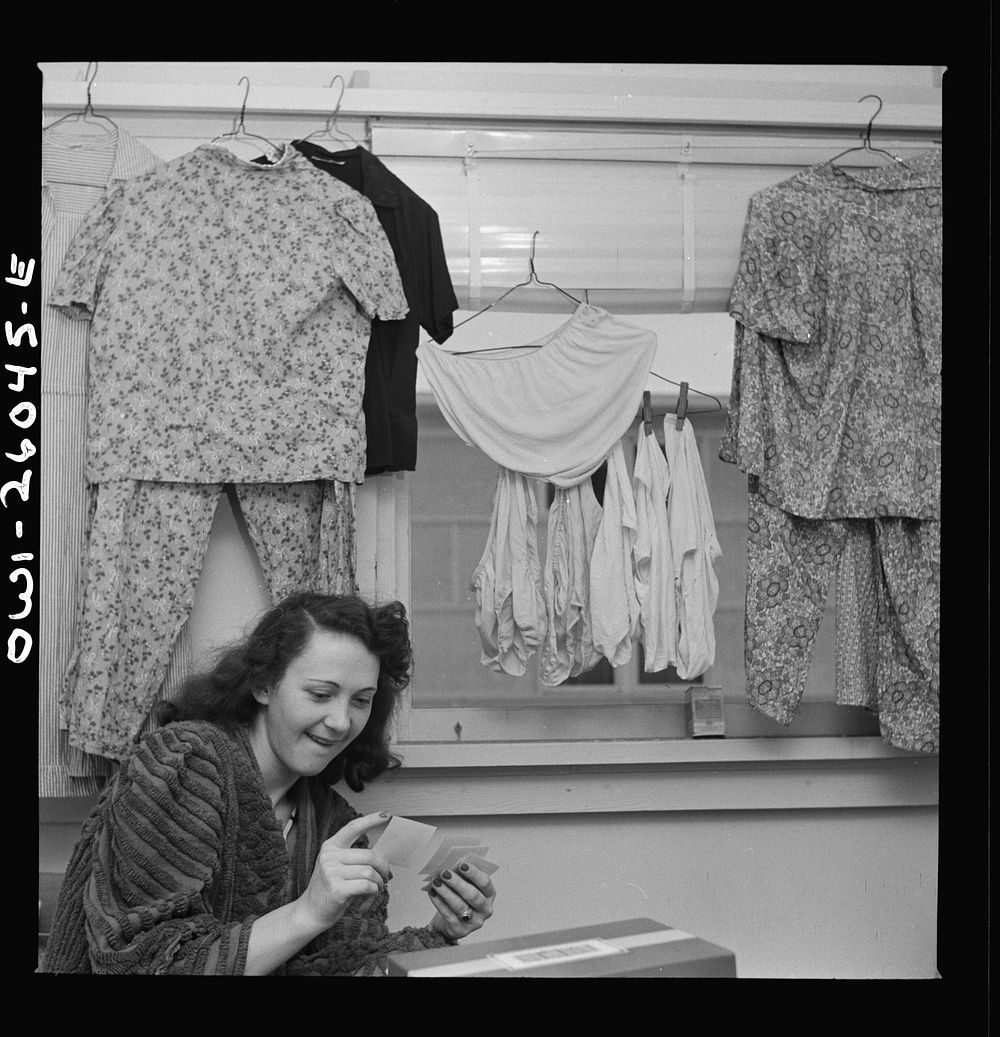 Arlington, Virginia. A girl looking at snapshots in her room at Idaho Hall, Arlington Farms, a residence for women who work…