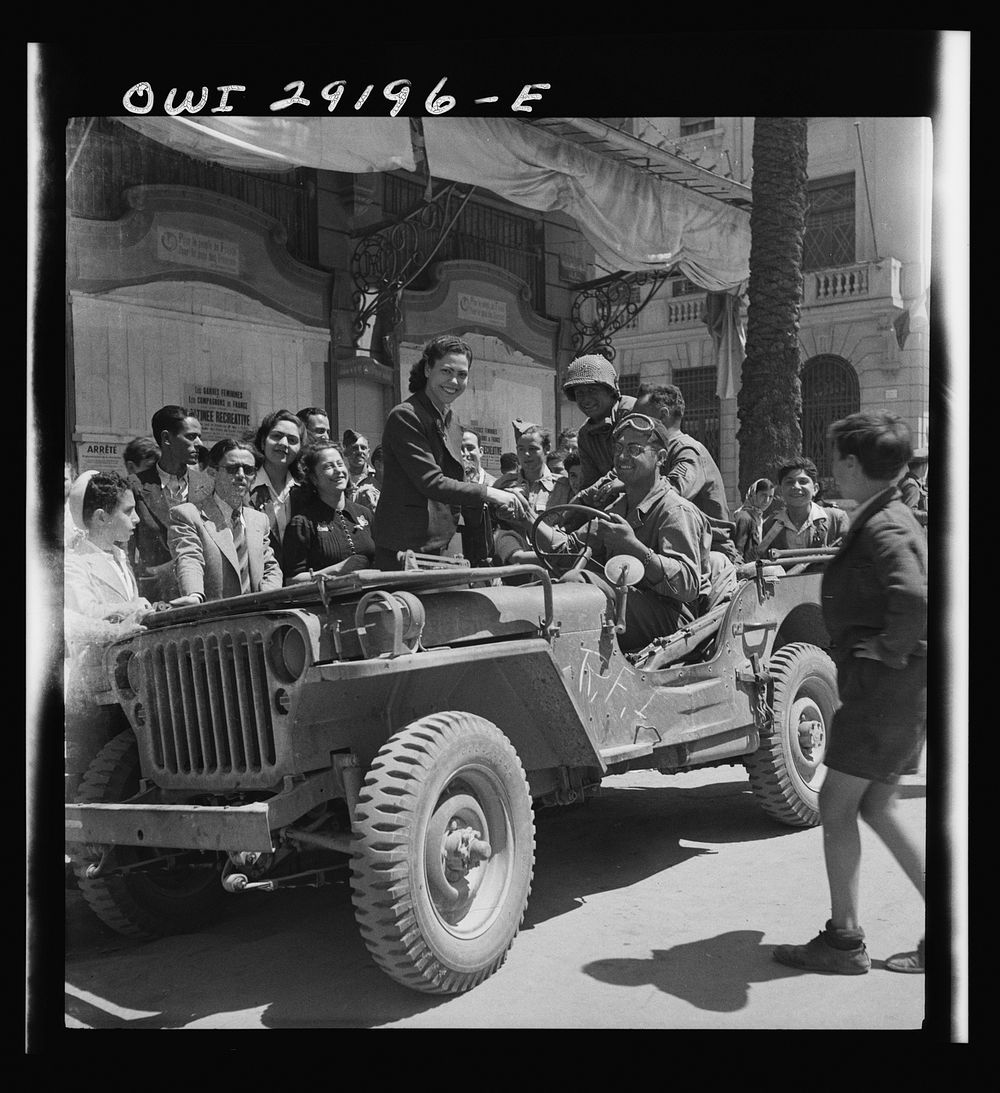 Girls climb on the Jeeps to greet American invading troops in the streets of Tunis. Sourced from the Library of Congress.