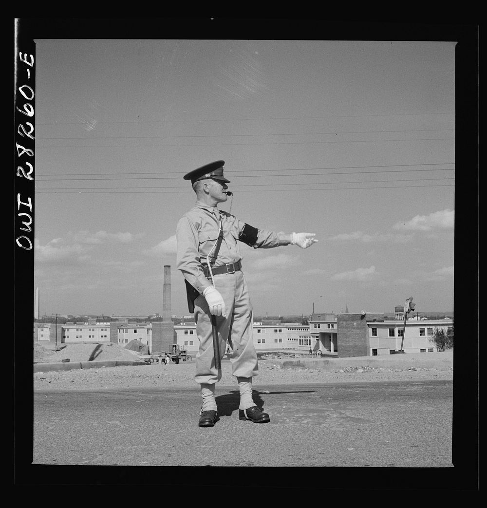 Arlington Farms, war duration residence halls. Military Police acting as traffic officer by the bus stop at Arlington Farms.…