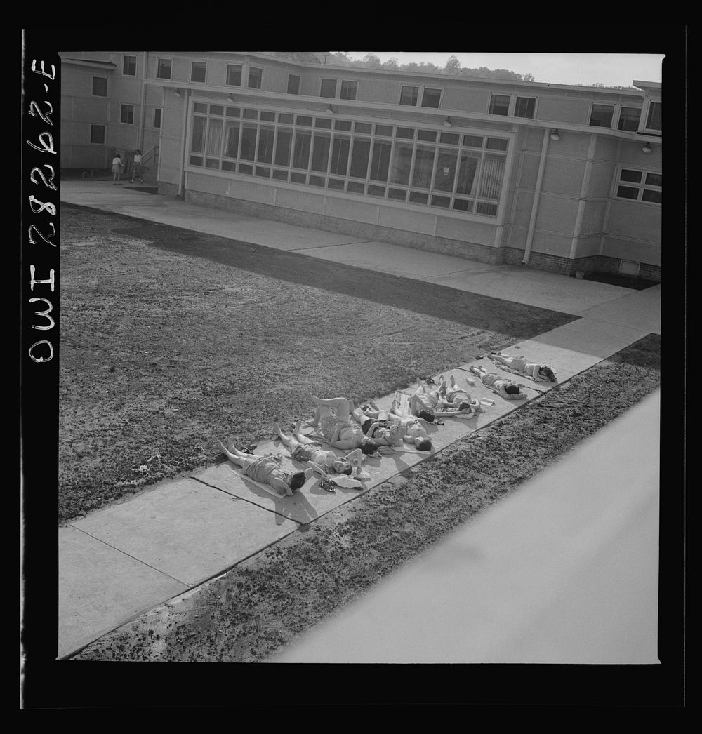 [Untitled photo, possibly related to: Arlington Farms, war duration residence halls. Sunbathers on the sidewalk in the back…