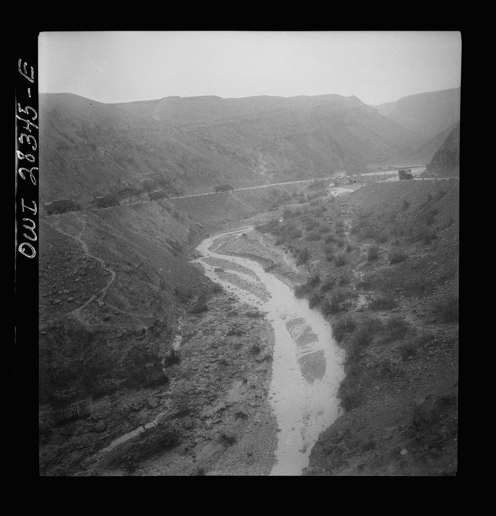 Somewhere in the Persian corridor. A United States Army truck convoy carrying supplies for Russia winding around a gorge in…