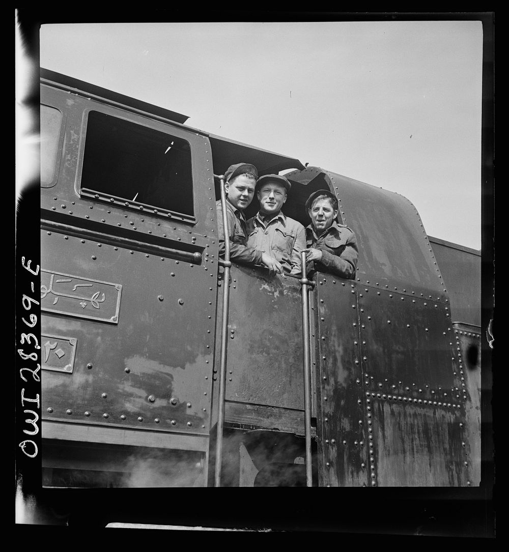 American, Russian and English engineers in the cab of an engine. Each of them has done his part in hurrying supplies enroute…