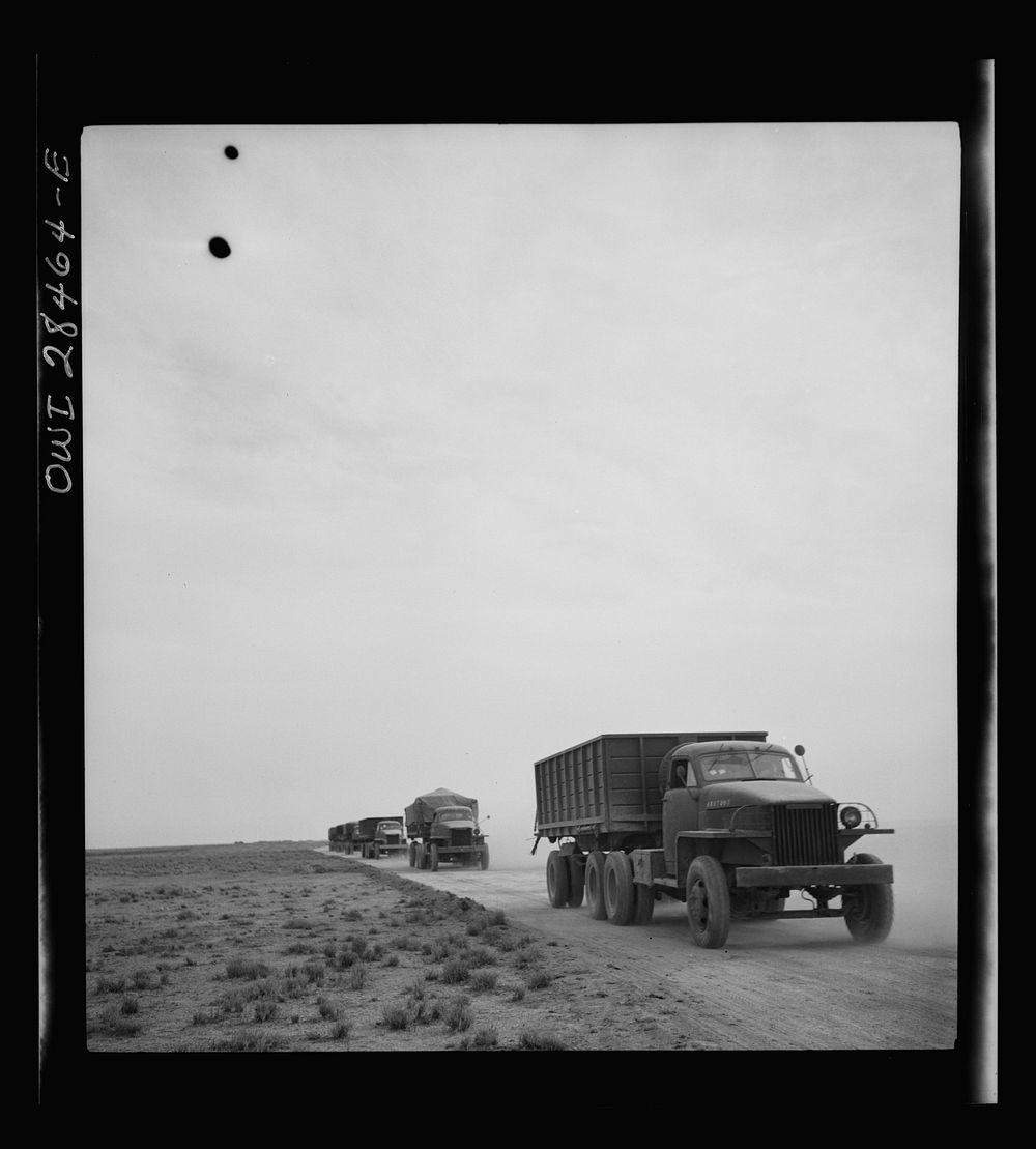 Somewhere in the Persian corridor. A United States Army truck convoy carrying supplies for Russia on a desert road. Sourced…