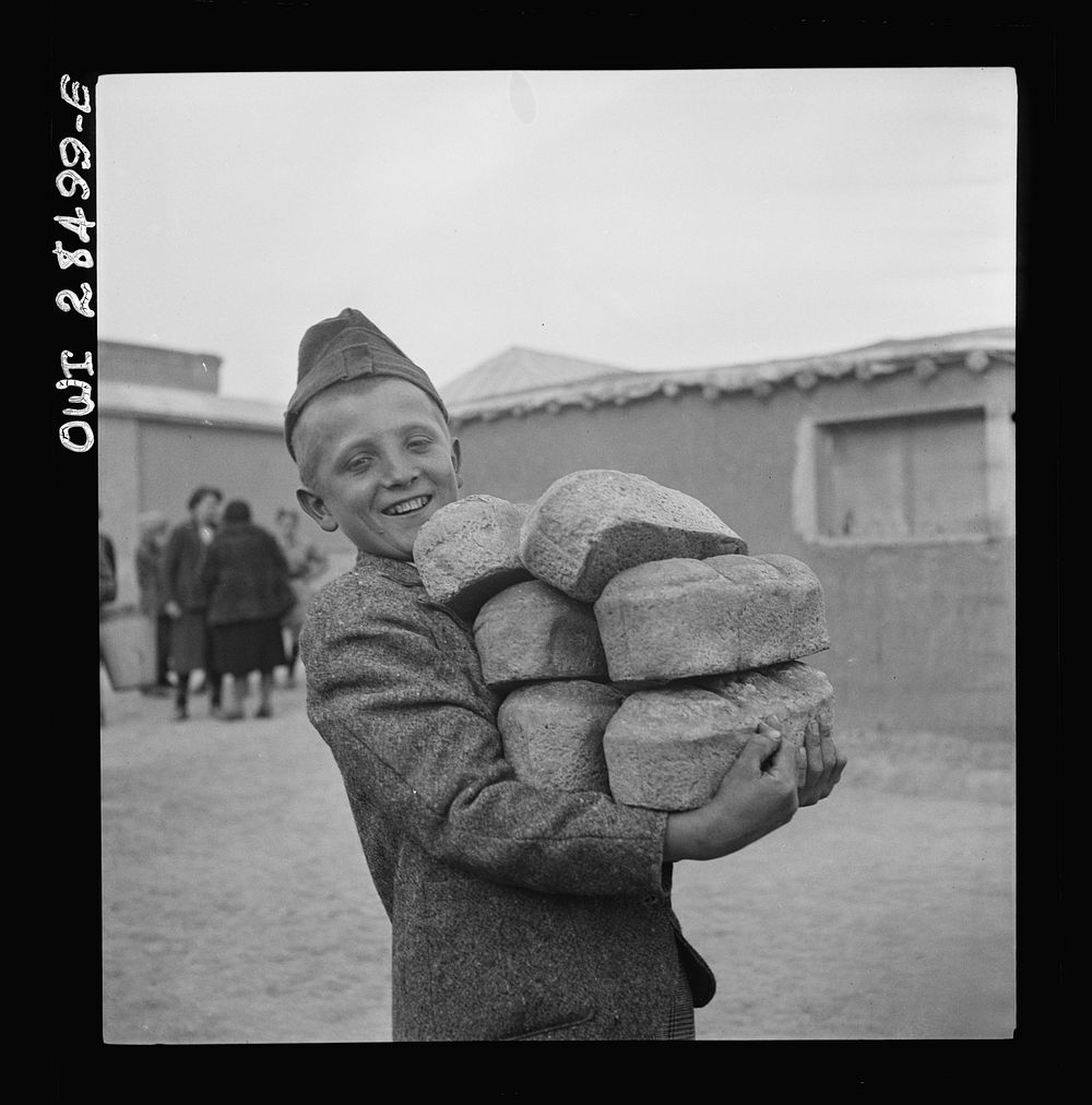Teheran, Iran. Polish youngster carrying an armload of loaves of bread made from Red Cross flour at an evacuation camp.…