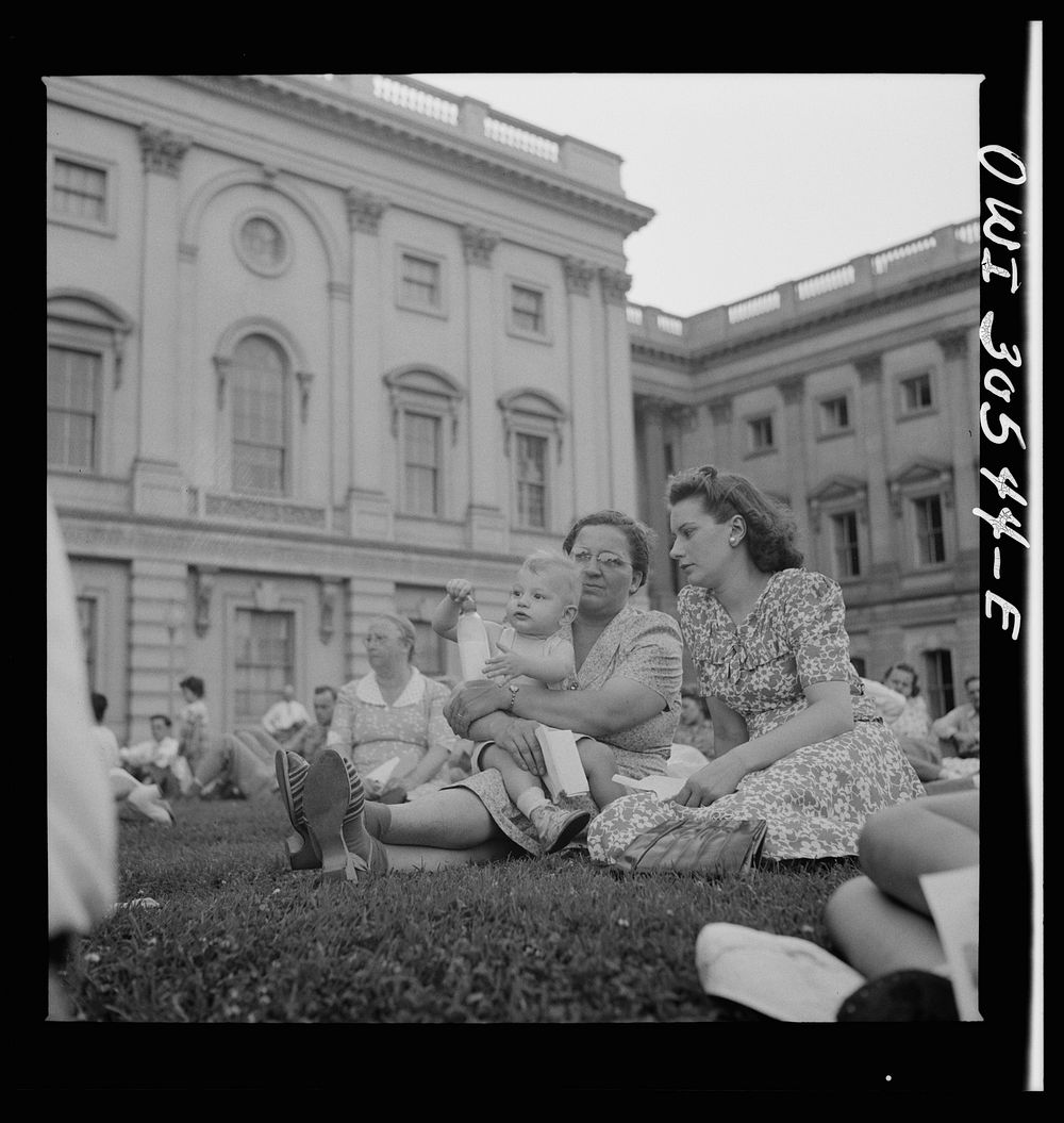 Washington, D.C. Mother, wife, and son of a trumpet player in the U.S. Army band at a concert in front of the Capitol.…