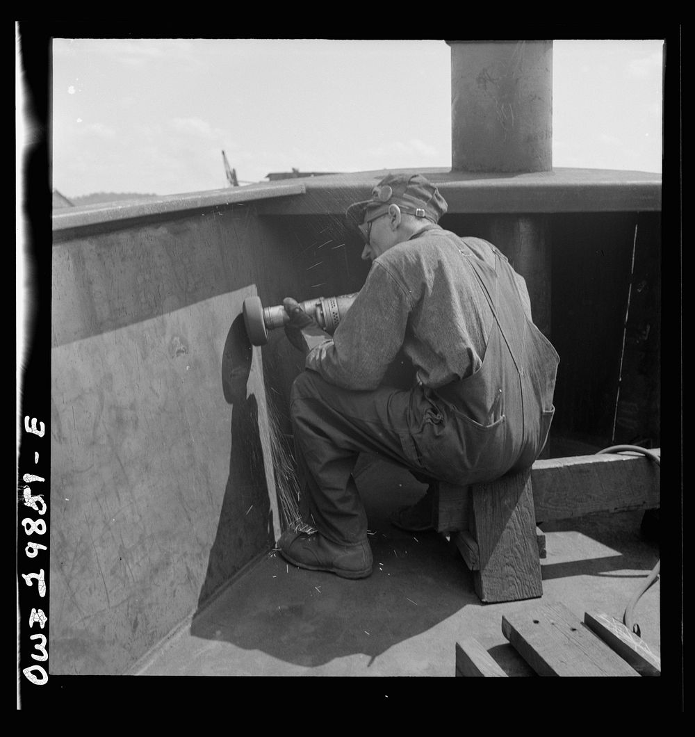 Point Pleasant, West Virginia. Burring operation on an LT boat at the Marietta Manufacturing Company. Sourced from the…