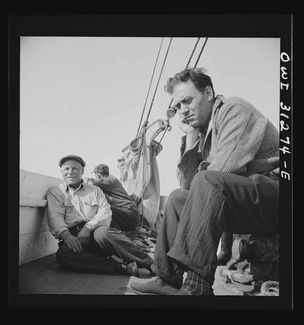 On board the fishing boat Alden out of Gloucester, Massachusetts. Fishermen sitting about the deck on the first morning.…