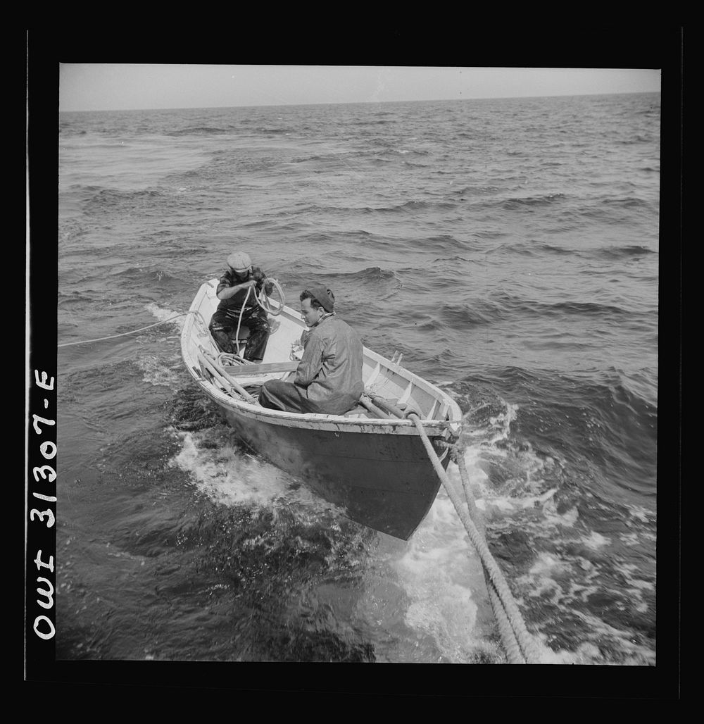On board the fishing boat Alden, out of Gloucester, Massachusetts. A dory with men, being towed during a mackerel chase.…