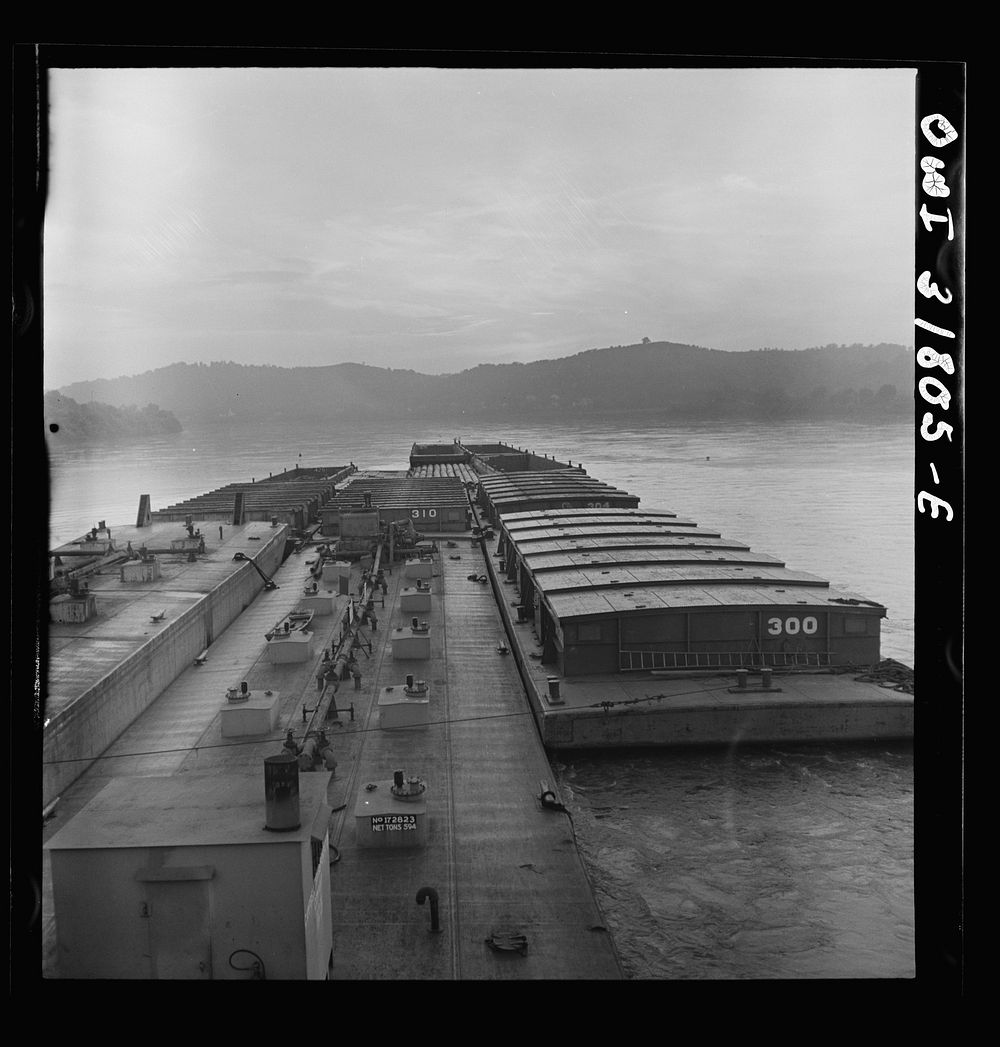 Barges in the tow of the towboat Ernest T. Weir going down the Ohio River to Cincinnati. Sourced from the Library of…