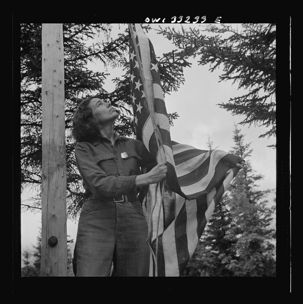 Gorham (vicinity), New Hampshire. Barbara Mortensen, a fire and airplane lookout on Pine Mountain, running up the colors.…